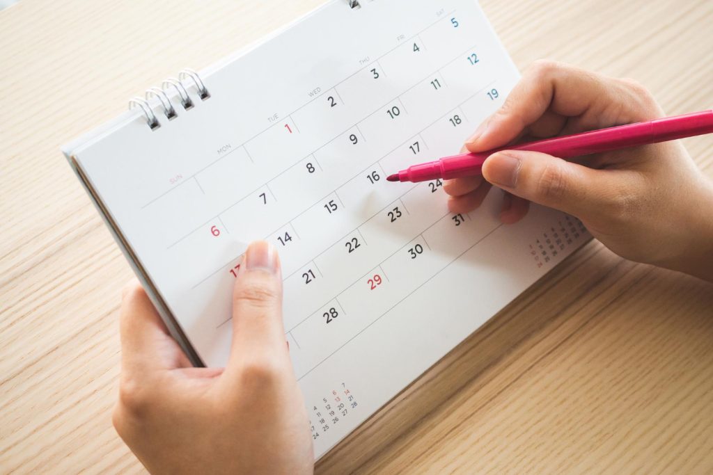 person holding a calendar and surrounding a date with a red pen
