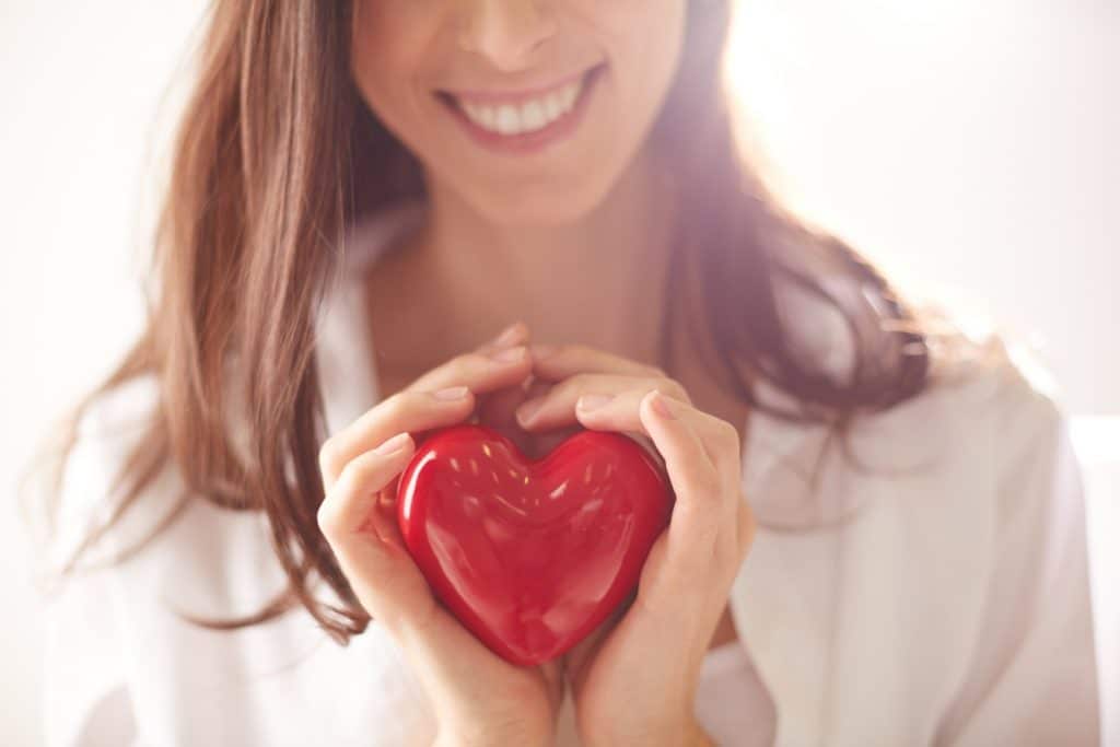 smiling woman holding a red heart in her hands